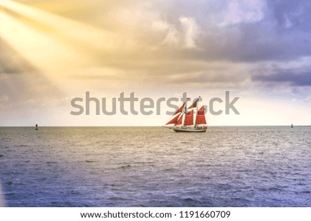 Vintage and exotic sailboat sailing in South Florida toward the sun rays