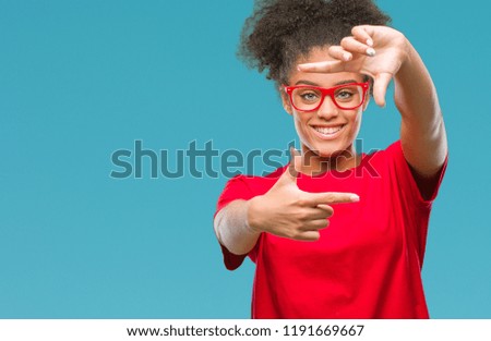 Young afro american woman wearing glasses over isolated background smiling making frame with hands and fingers with happy face. Creativity and photography concept.