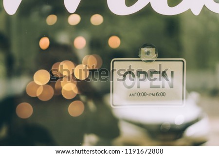 A business sign that says 'Open' on Cafe / Restaurant window and bokeh background.vintage tone.