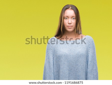 Young beautiful caucasian woman wearing winter sweater over isolated background with serious expression on face. Simple and natural looking at the camera.