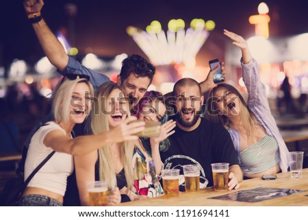Group of friends drinking beer and taking selfie at music festival