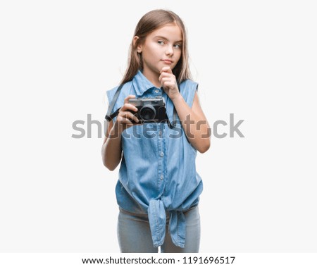 Young beautiful girl taking photos using vintage camera over isolated background serious face thinking about question, very confused idea