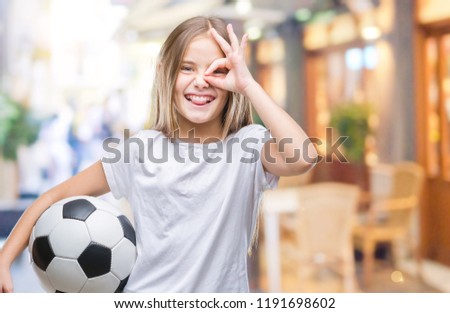 Young beautiful girl holding soccer football ball over isolated background with happy face smiling doing ok sign with hand on eye looking through fingers