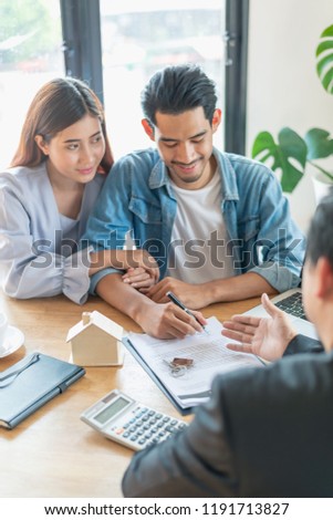 Business concept : Home rental or sell company staff showing house rental contract agreement document to the customer before sign at the office. Document in picture is fake.