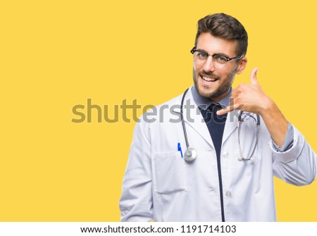Young handsome doctor man over isolated background smiling doing phone gesture with hand and fingers like talking on the telephone. Communicating concepts.