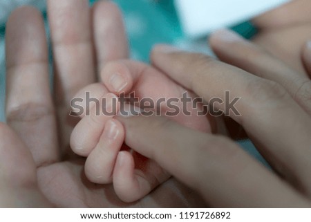 New born baby holding her mother finger.