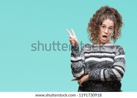 Beautiful brunette curly hair young girl wearing glasses over isolated background smiling with happy face winking at the camera doing victory sign. Number two.