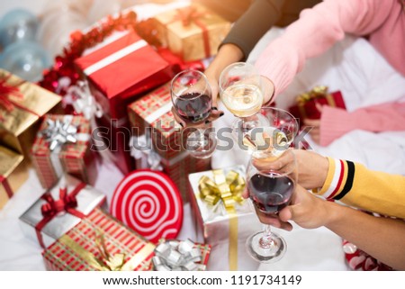 Hands of people celebrating New year party in home with wine drinking glasses and present background. New year eve and Christmas party concept. Happiness and Friendship and Funny together. Clink glass