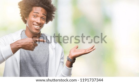 Afro american man wearing sweatshirt over isolated background amazed and smiling to the camera while presenting with hand and pointing with finger.