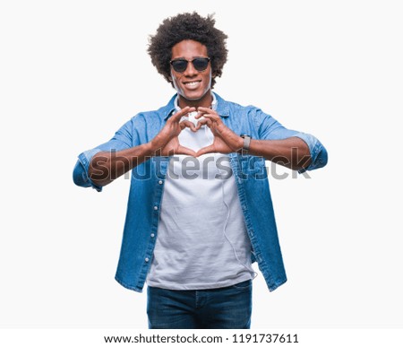 Afro american man wearing headphones listening to music over isolated background smiling in love showing heart symbol and shape with hands. Romantic concept.