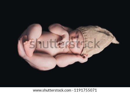 portrait of newborn baby in a yellow or gold hat on a black background. Newborn fashion