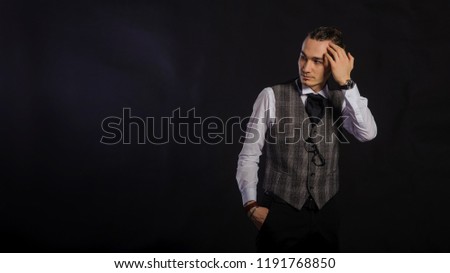 The handsome caucasian young man in a white shirt and suit standing, black background