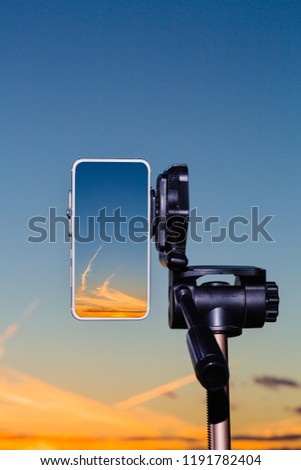 Smartphone on tripod capturing image of stunning sundown in vertical mode
