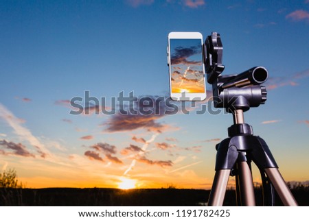 Using smartphone on tripod to capturing image of stunning sundown in vertical mode