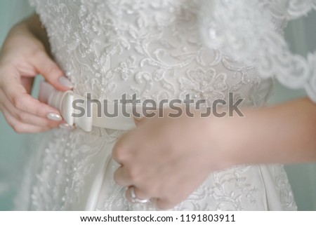 The bride shows a beautiful wedding dress belt