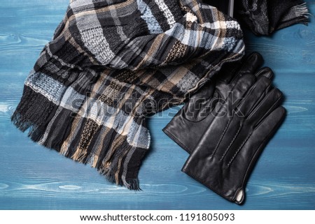 Men's gloves and scarf on a blue wooden background