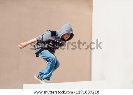 Teenage boy in the hood on a street in a big city next to a high-rise building alone. concept of a teenager parkour life. parkour jump portrait on the street in the big city close view