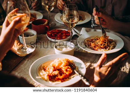 Friends having a pasta dinner at home of at a restaurant. Royalty-Free Stock Photo #1191840604
