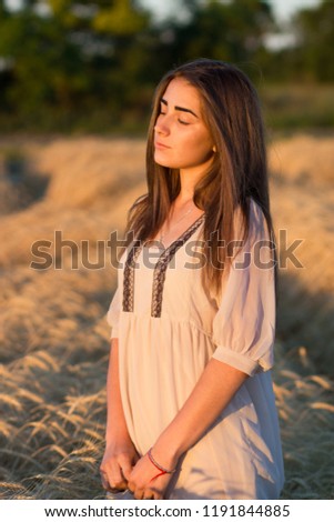 Beautiful girl in a field of wheat in a white dress, a perfect picture in the style lifestyle.