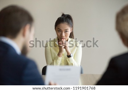 Nervous young Asian job applicant wait for recruiters question during interview in office, worried intern or trainee feel stressed applying for open position, meeting with hr managers. Hiring concept Royalty-Free Stock Photo #1191901768