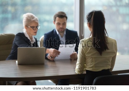 Back view of female candidate apply for position, interview in modern office, recruiters consider applicant candidature, reading resume, HR managers look through employee cv. Hiring concept Royalty-Free Stock Photo #1191901783