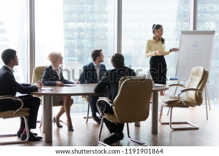 Young Asian employee present business project to interested diverse colleagues at office negotiations, millennial coach train workers, making presentation on whiteboard at meeting. Education concept Royalty-Free Stock Photo #1191901864