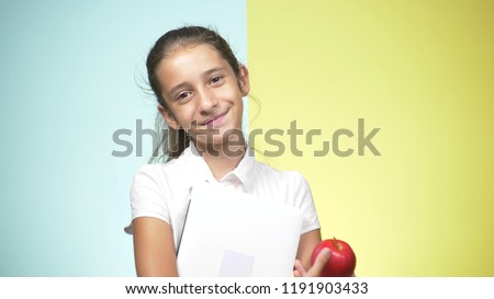 Portraits of a teenage girl in school uniform on a colored background. Funny girl. concept of learning. A teenager is holding books looking at the camera and smiling. copy space