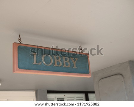Green and gold lobby sign hanging outdoors at entrance of hotel