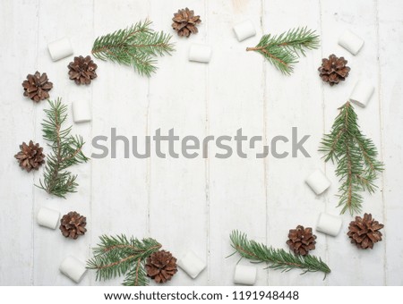 Christmas composition. Frame made of pine branches, marshmallows and fir cones on a white background. Flat lay, top view, copy space.