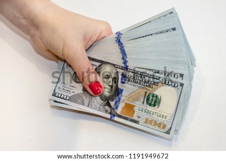 Big stack of one hundred dollar banknotes in female hand. Close up view from top on white background.
