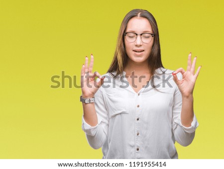 Young caucasian beautiful business woman wearing glasses over isolated background relax and smiling with eyes closed doing meditation gesture with fingers. Yoga concept.
