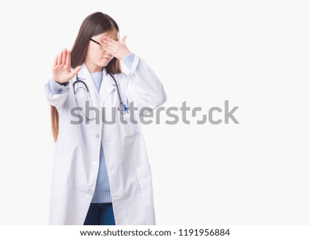 Young Chinese doctor woman over isolated background covering eyes with hands and doing stop gesture with sad and fear expression. Embarrassed and negative concept.