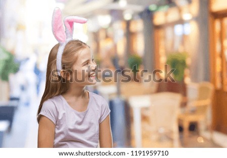 Young beautiful girl wearing easter bunny ears over isolated background looking away to side with smile on face, natural expression. Laughing confident.