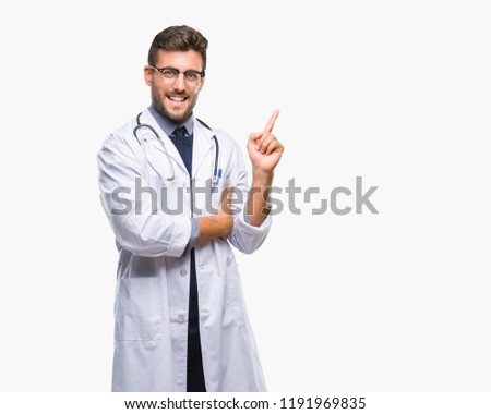 Young handsome doctor man over isolated background with a big smile on face, pointing with hand and finger to the side looking at the camera.