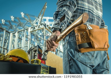 Caucasian Steel Construction Worker with Large Professional Hammer in Front of Construction Site.