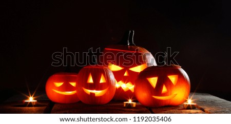 Halloween pumpkin head jack o lantern and candles on black background
