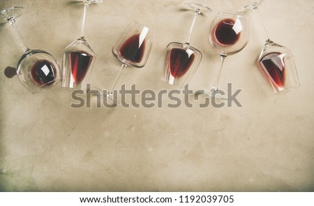 Flat-lay of red wine in glasses over grey concrete background, top view, copy space. Bojole nouveau, wine bar, winery, wine degustation concept