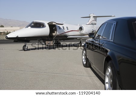 Limousine and private jet on landing strip Royalty-Free Stock Photo #119204140