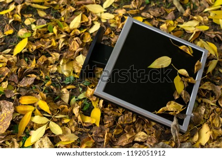 Monitor from the computer is lies on the autumn yellow foliage in the yard on the street