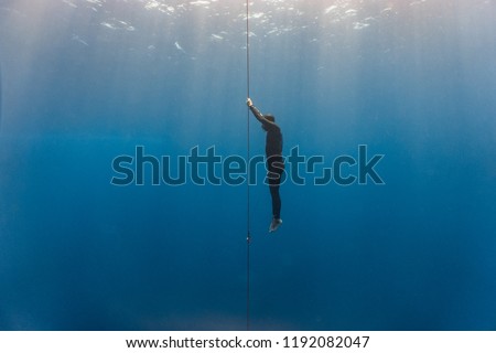 Free diver ascends to the surface by pulling the dive line Royalty-Free Stock Photo #1192082047