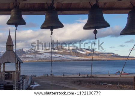 A wallpaper of four church bells at the Russian Orthodox church in Barentsburg, Spitsbergen, Svalbard, Norway, with he snow capped mountains across Grønfjorden (Green Fjord or Green Harbour) behind. Royalty-Free Stock Photo #1192100779