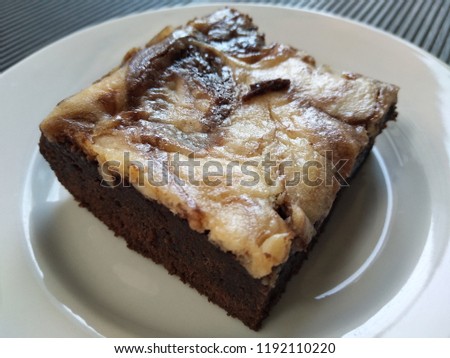 Cheese brownies on white plate. Homemade dessert for chocolate lover. Served on white plate on the table. Sweet and moist taste. Bakery in the coffee shop.