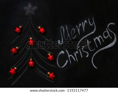 chalk-drawn Christmas tree on a slate with real red Christmas balls and chalk-written inscription Merry Christmas . Concept of New Year and Christmas.