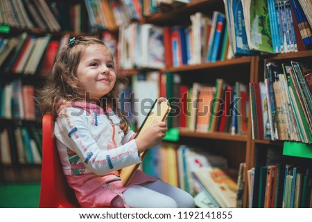 Cute girl reading book in library.