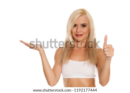 young pretty blonde woman holding imaginary object and showing thumbs up on white background