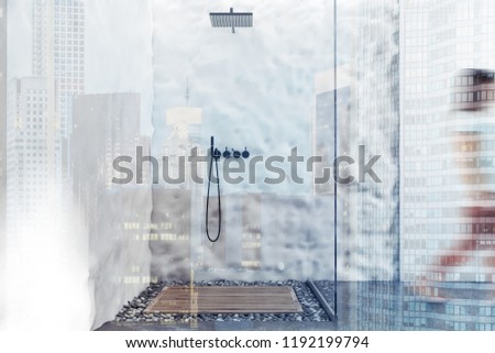 Young woman walking in white tile and crude wall bathroom interior with glass wall shower and concrete and pebble floor. Toned image double exposure blur