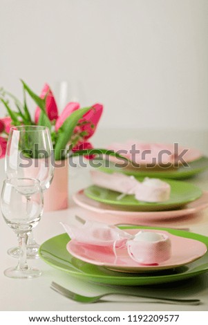 Happy easter. Decor and table setting of the Easter table is a vase with pink tulips and dishes of pink and green color. Selective focus.