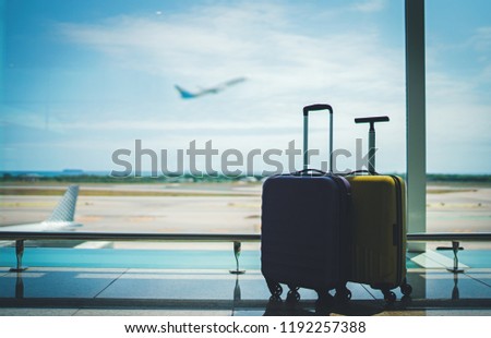 Traveling by airplane. Two suitcases in airport departure lounge, vacation concept or business travel, airplane taking off on the background, luggage in waiting area airport terminal Royalty-Free Stock Photo #1192257388