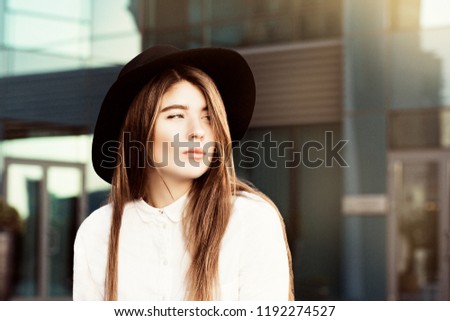 Outdoor portrait of a thoughtful teenage girl wearing black hat and white shirt