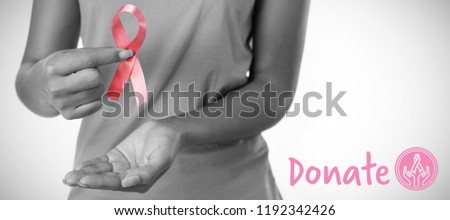 Graphic image of donate text with breast cancer awareness ribbon against woman holding ribbon between fingers for breast cancer awareness